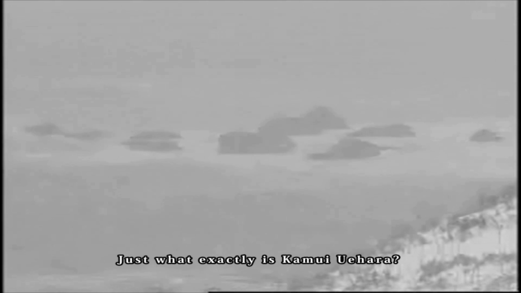 Screenshot from "LifeCut." A still of black-and-white footage of the ocean lapping stones in winter in Hokkaido. Subtitles read, "Just what exactly is Kamui Uehara?"